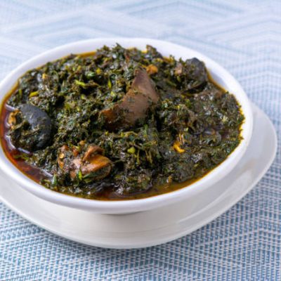 Close up shot of Efik tribe (Nigeria) Afang soup with beef and snails and prawns on a textured background